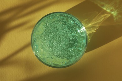 Photo of Jar of cosmetic gel on yellow background, top view