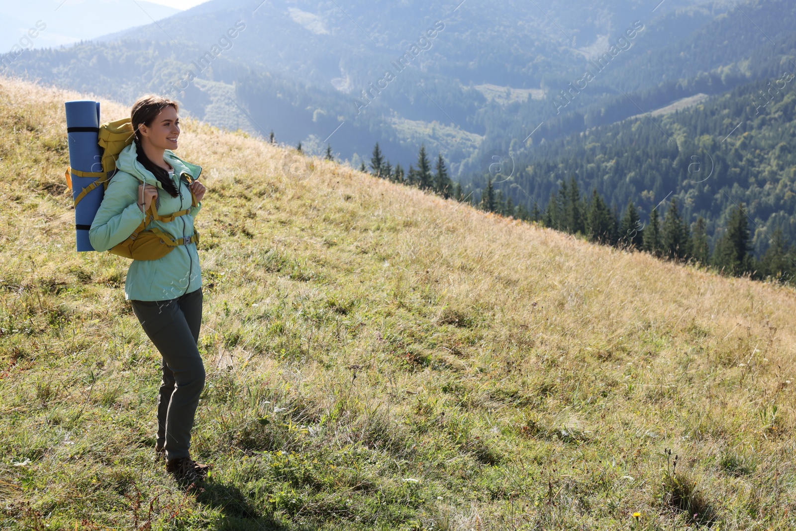 Photo of Tourist with backpack and sleeping pad in mountains on sunny day