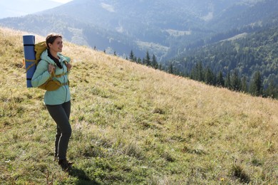 Tourist with backpack and sleeping pad in mountains on sunny day