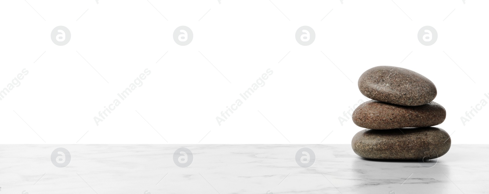 Photo of Stack of spa stones on marble table against white background. Space for text