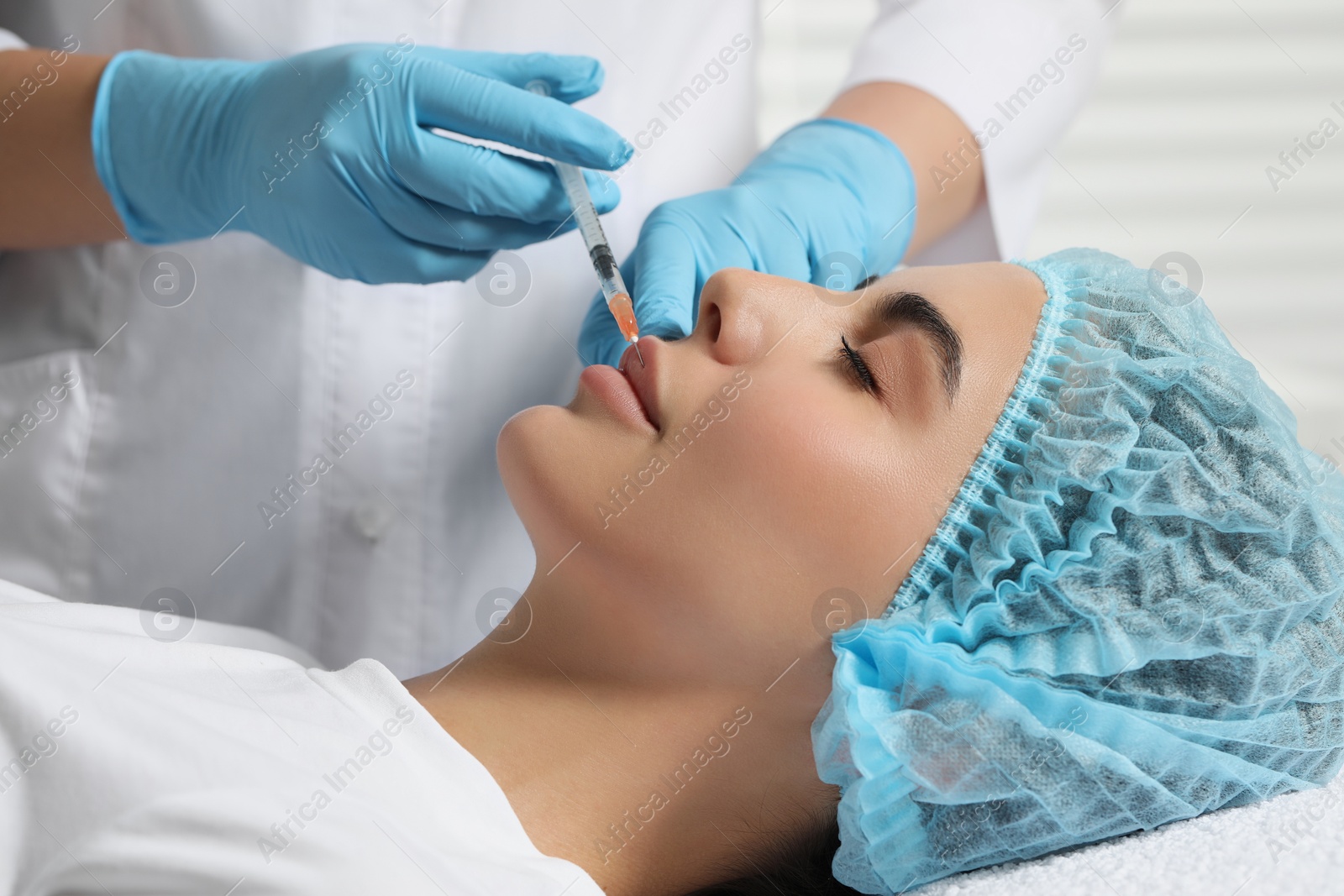 Photo of Doctor giving lips injection to young woman in clinic. Cosmetic surgery