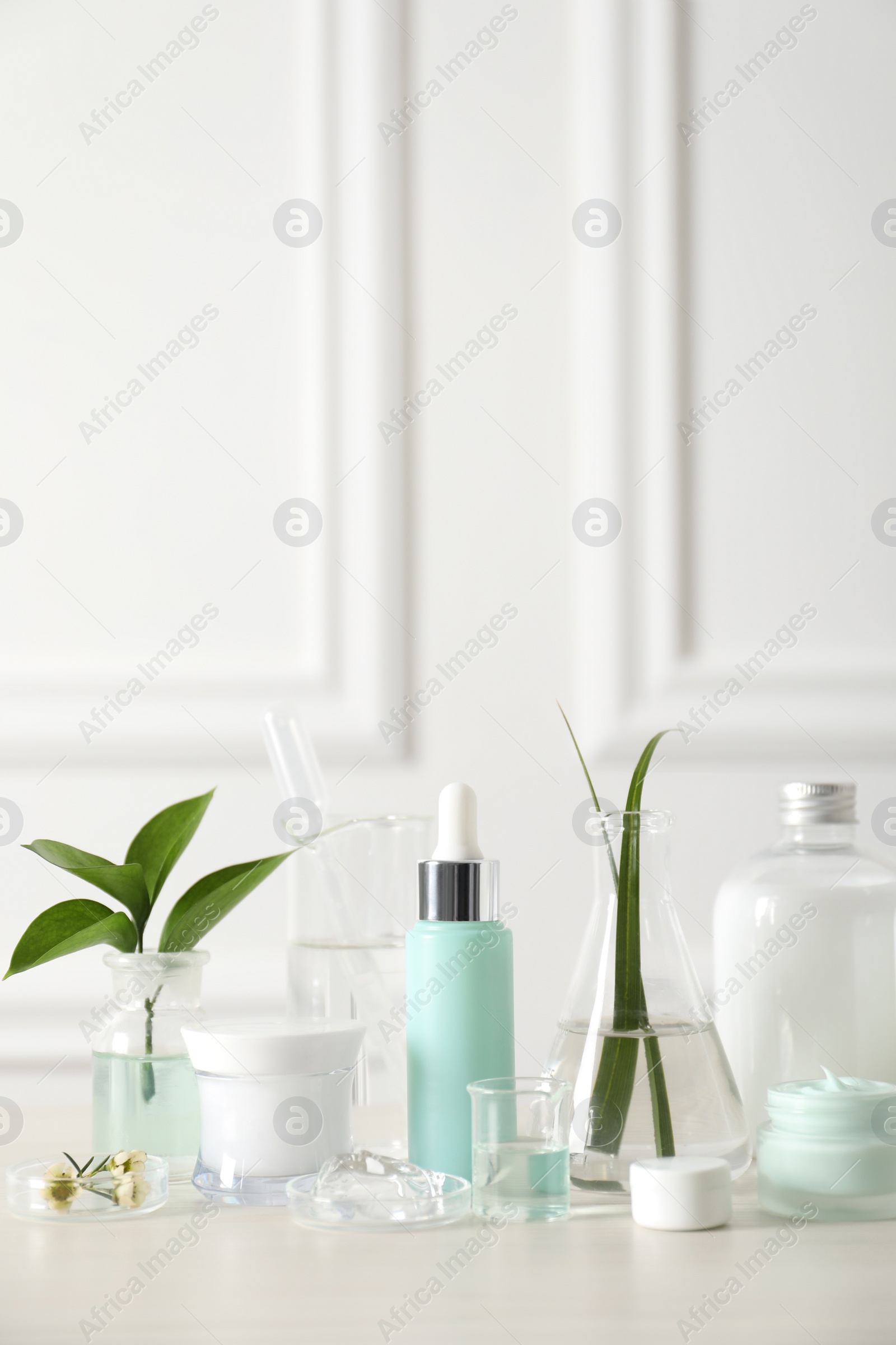 Photo of Natural ingredients for cosmetic products and laboratory glassware on white table