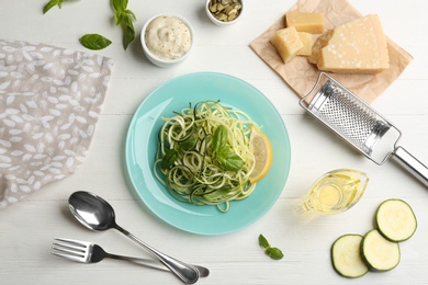 Photo of Delicious zucchini pasta with basil and lemon served on white wooden table, flat lay