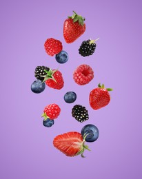 Image of Many different fresh berries falling on orchid color background