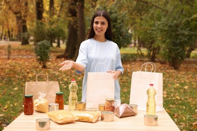 Photo of Portrait of volunteer with paper bag and food products on table in park
