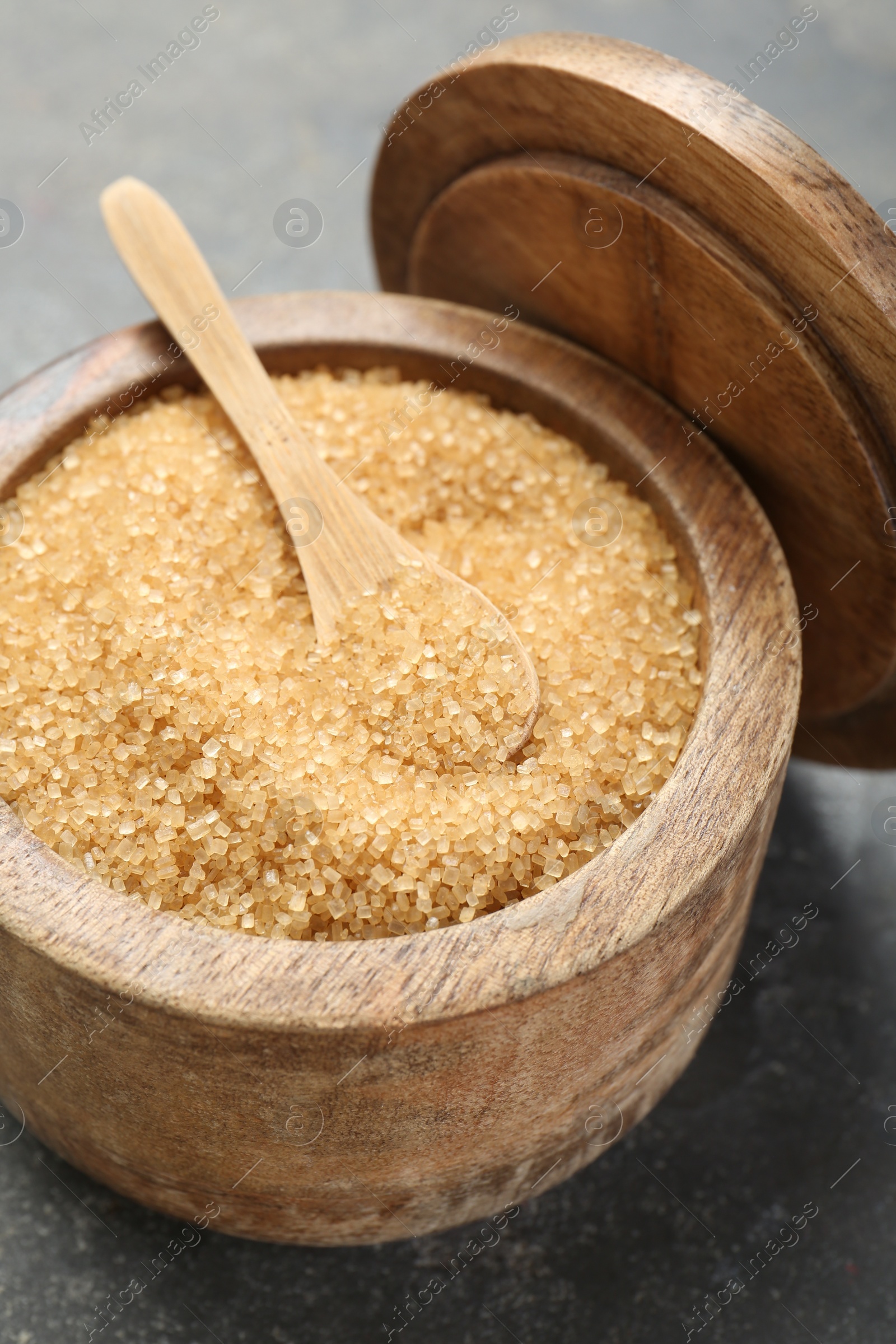 Photo of Brown sugar in bowl and spoon on grey table, closeup