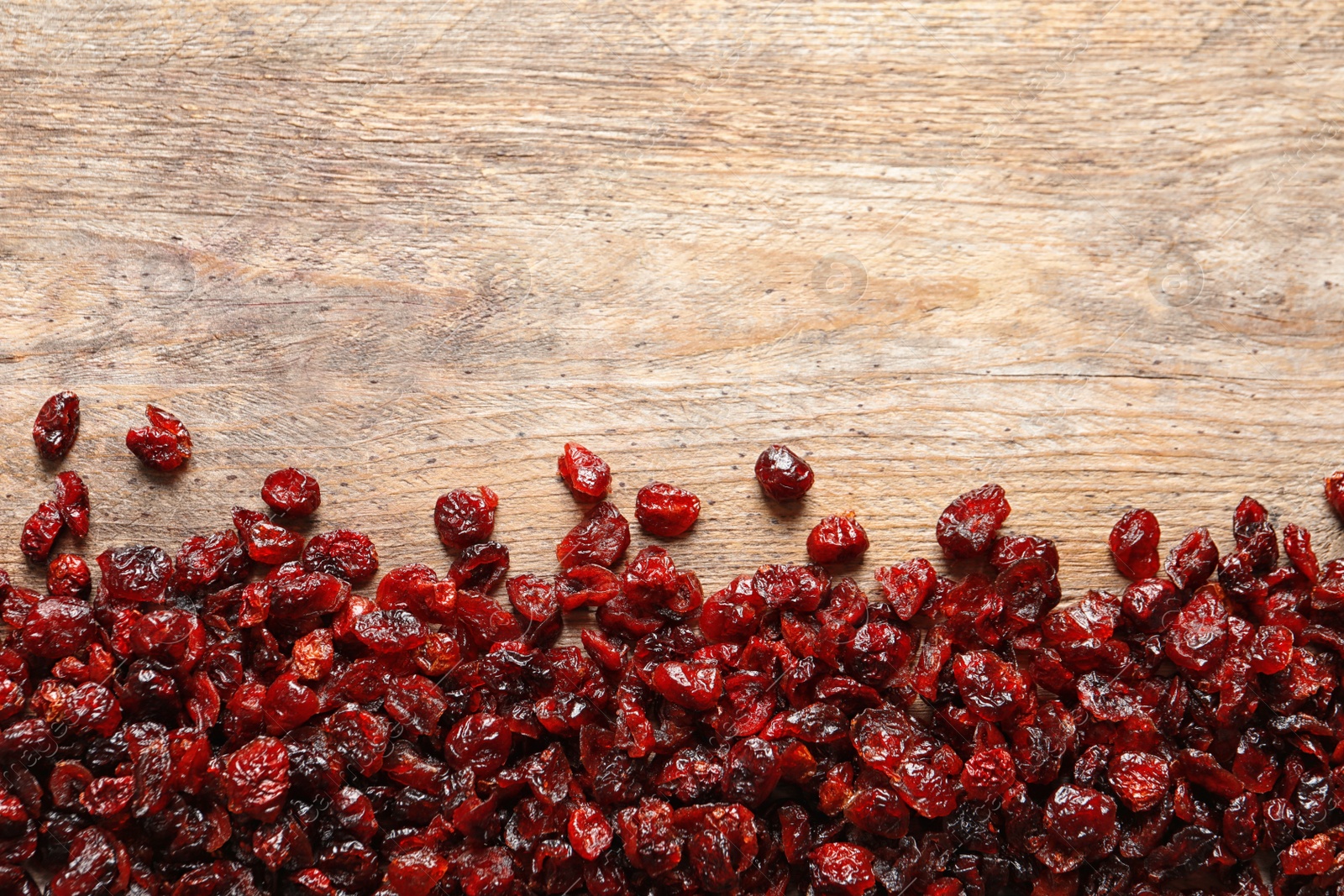 Photo of Tasty cranberries on wooden background, top view with space for text. Dried fruit as healthy snack