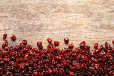 Photo of Tasty cranberries on wooden background, top view with space for text. Dried fruit as healthy snack