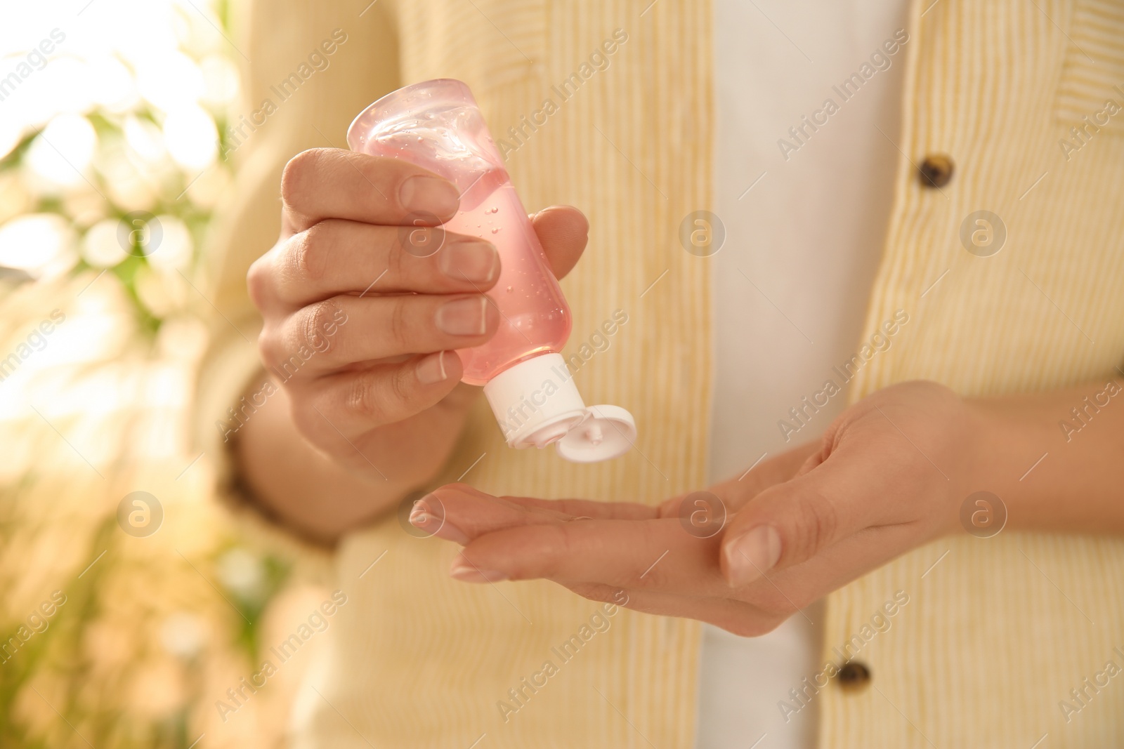 Photo of Young woman applying antiseptic gel outdoors, closeup