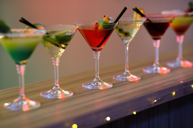 Different martini cocktails on table against blurred background