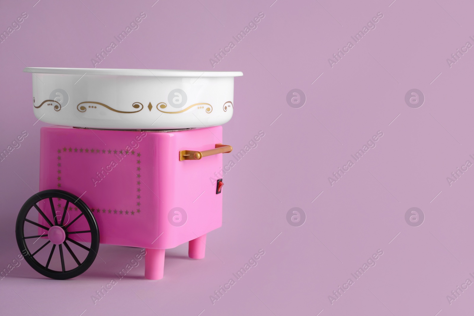 Photo of Portable candy cotton machine on violet background, space for text