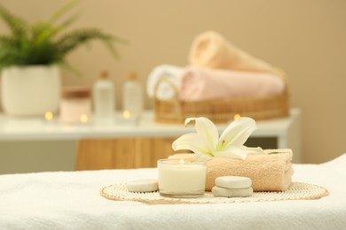 Photo of Beautiful spa composition with burning candle and stones on massage table in wellness center. Space for text