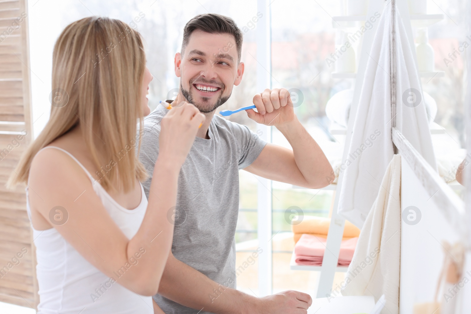 Photo of Young couple brushing teeth together in bathroom