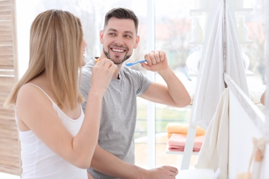 Young couple brushing teeth together in bathroom