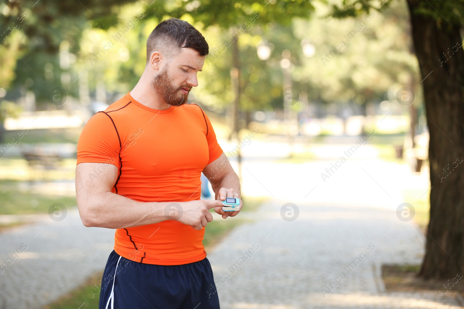 Photo of Young man checking pulse after workout in park