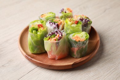Plate with different delicious spring rolls wrapped in rice paper on white wooden table