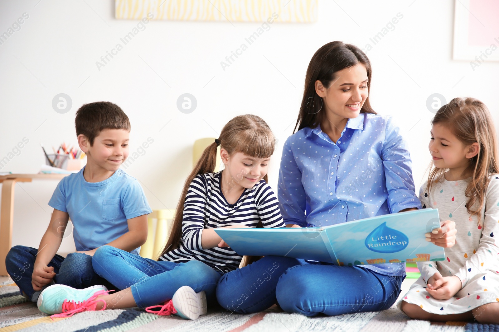 Photo of Cute little children with teacher in classroom at school