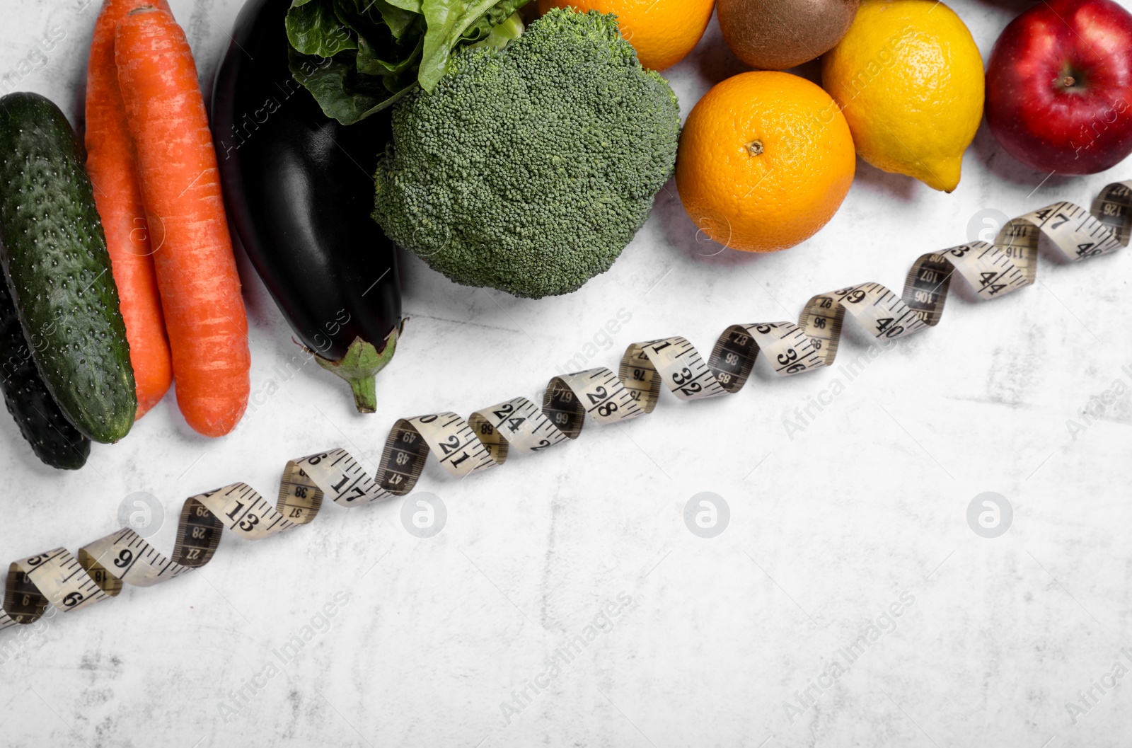 Photo of Measuring tape, fresh fruits and vegetables on light gray textured table, flat lay with space for text. Low glycemic index diet