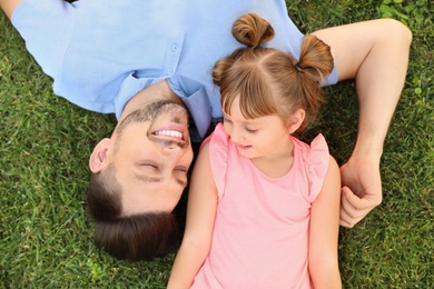 Father with his cute child on green grass in park, top view. Happy family