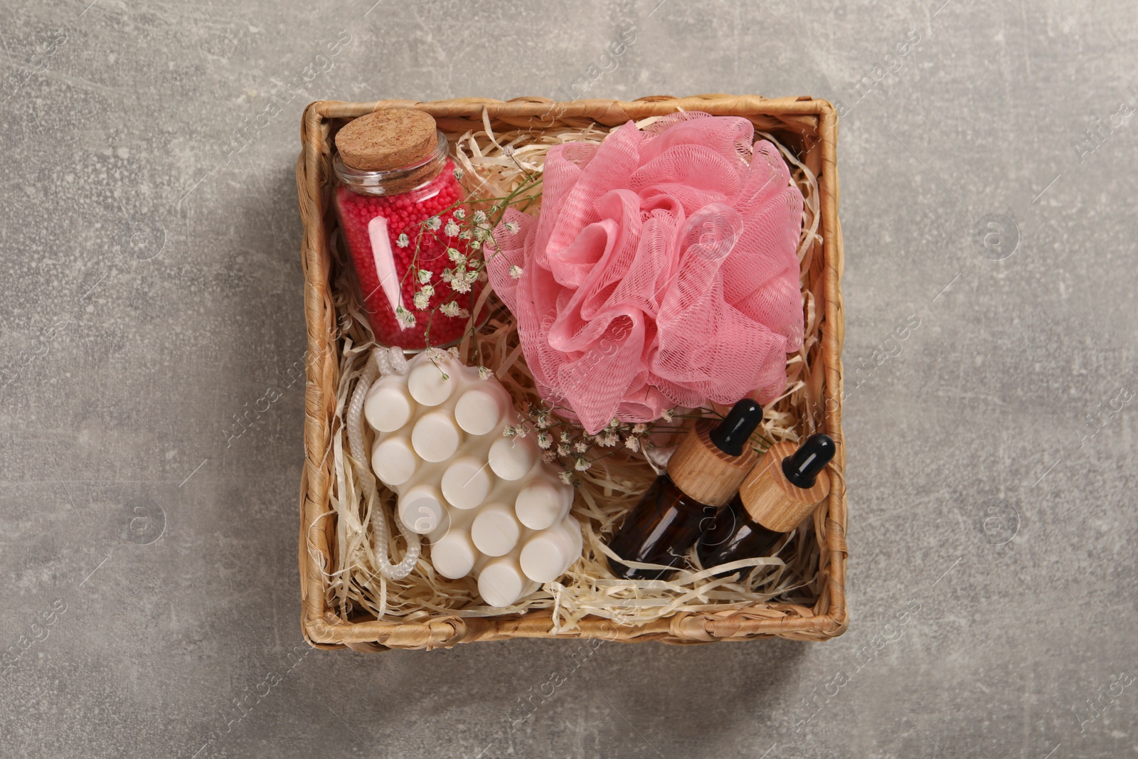 Photo of Spa gift set of different luxury products in wicker basket on grey table, top view