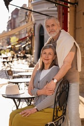Photo of Affectionate senior couple sitting in outdoor cafe