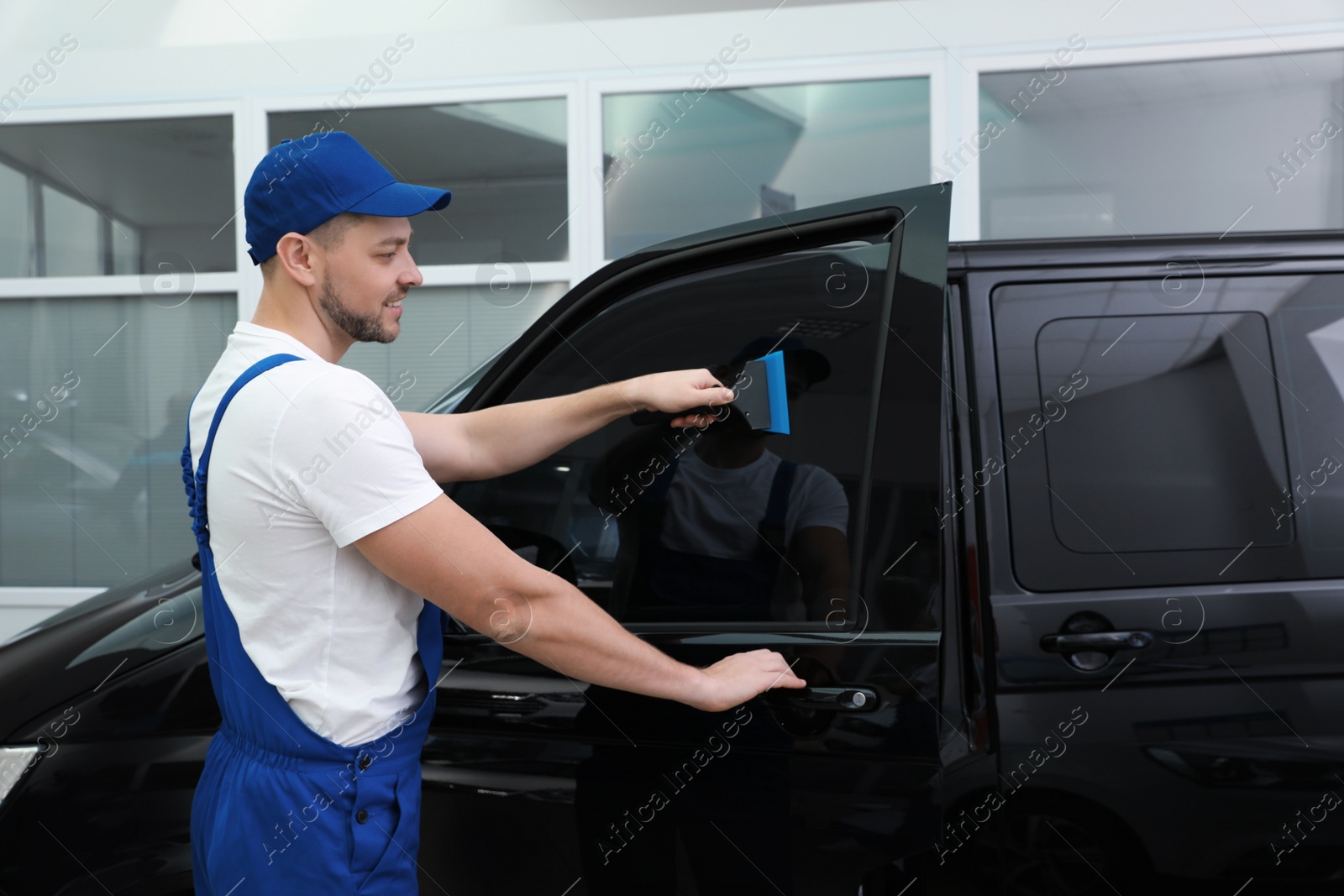 Photo of Worker tinting car window with foil in workshop