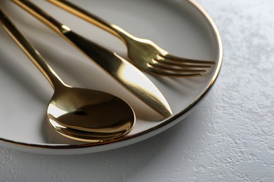 Photo of Plate with shiny cutlery on white table, closeup