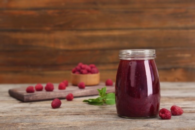 Photo of Jar with delicious raspberry jam on table