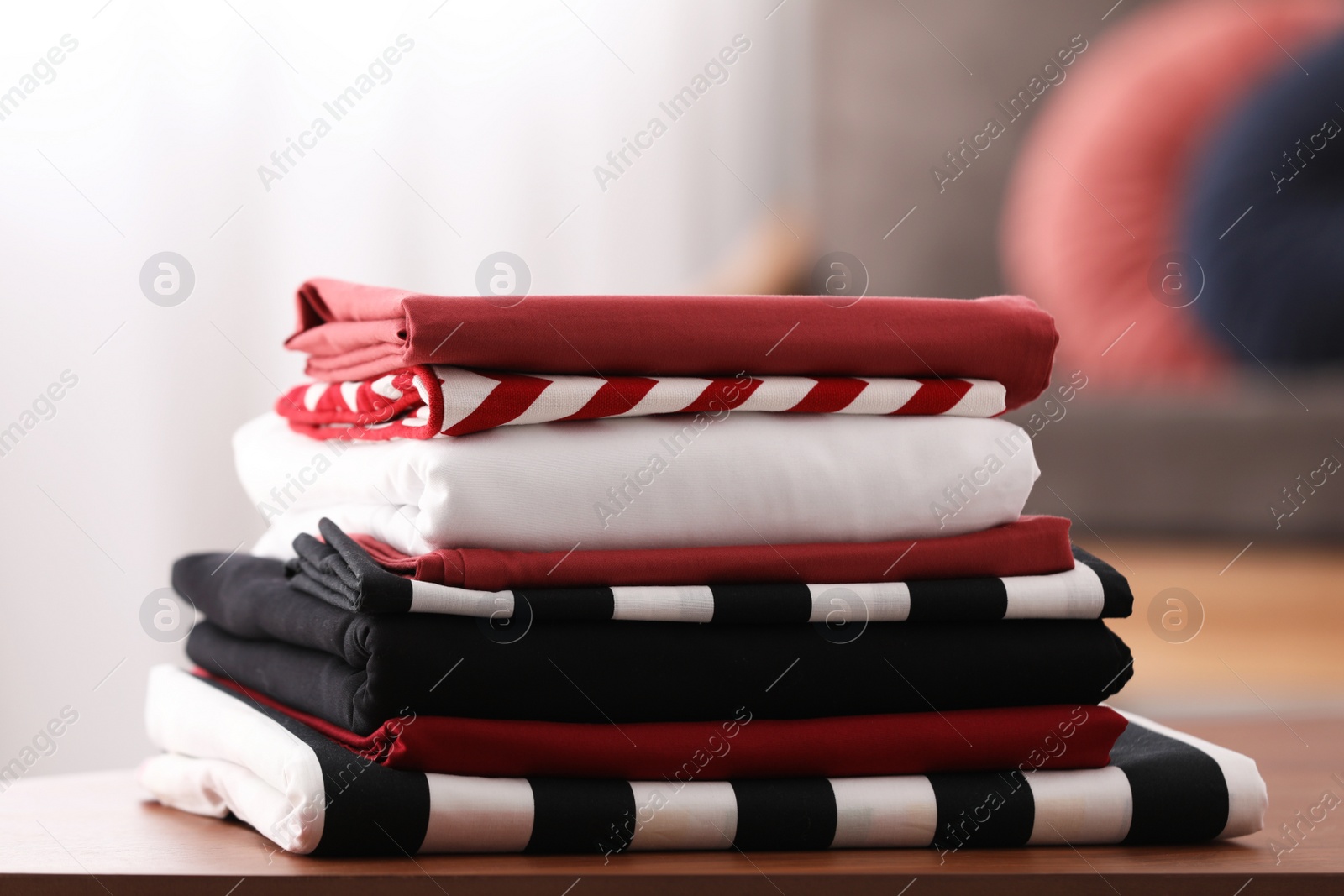 Photo of Clean color folded bed linens on table indoors