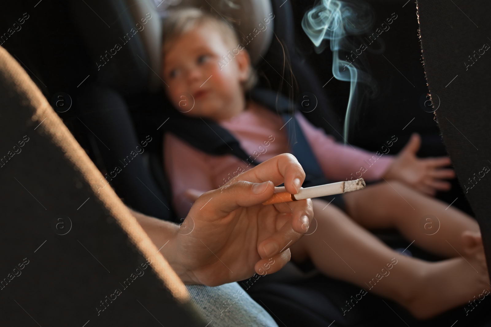 Photo of Mother with cigarette and child in car, closeup. Don't smoke near kids