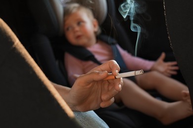 Photo of Mother with cigarette and child in car, closeup. Don't smoke near kids