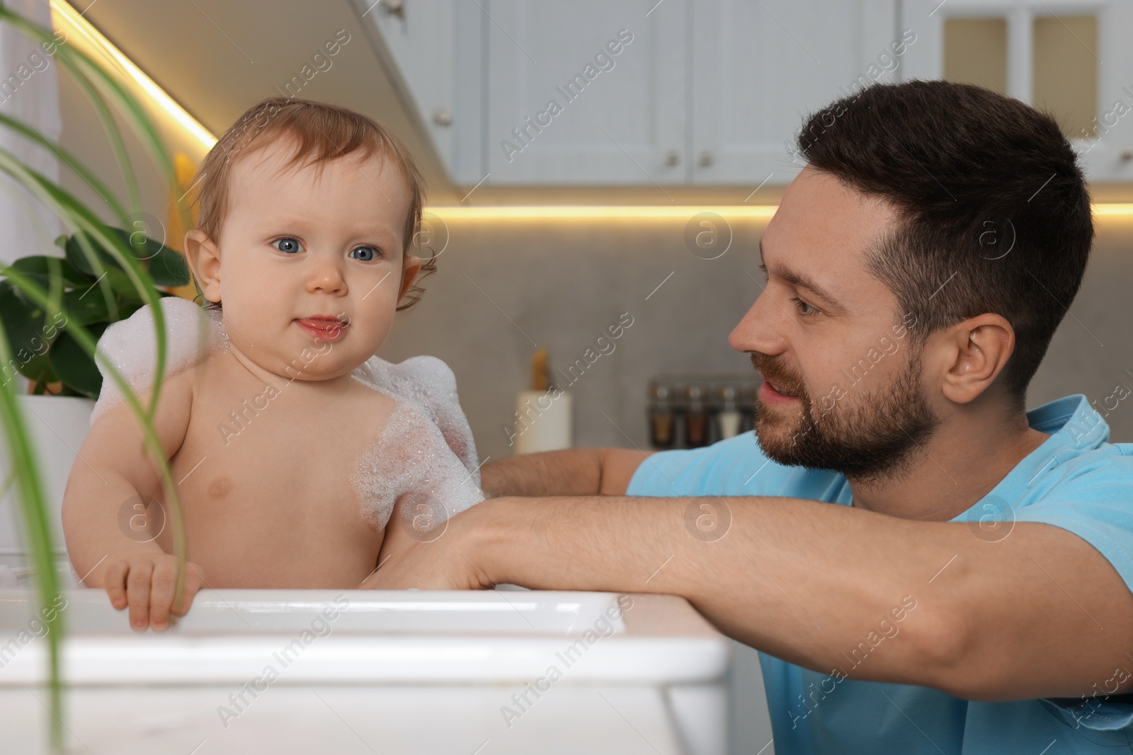 Photo of Father washing his little baby in sink at home