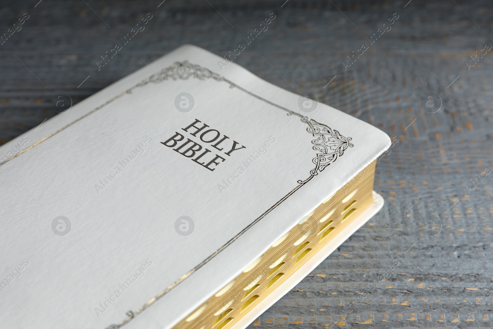 Photo of Old hardcover Bible on grey wooden table, closeup. Religious book