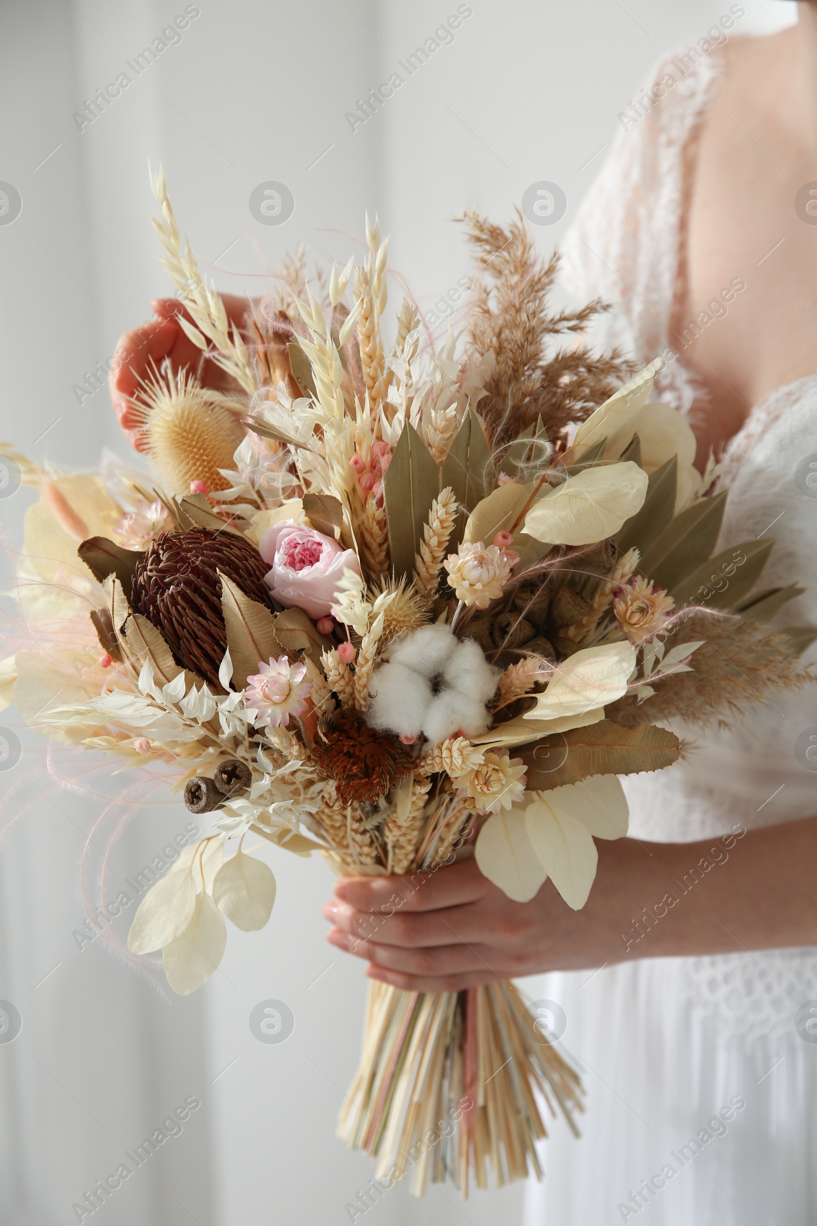 Photo of Bride holding beautiful dried flower bouquet at home, closeup