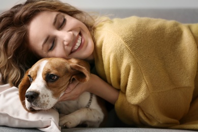 Photo of Young woman with her dog resting on sofa at home