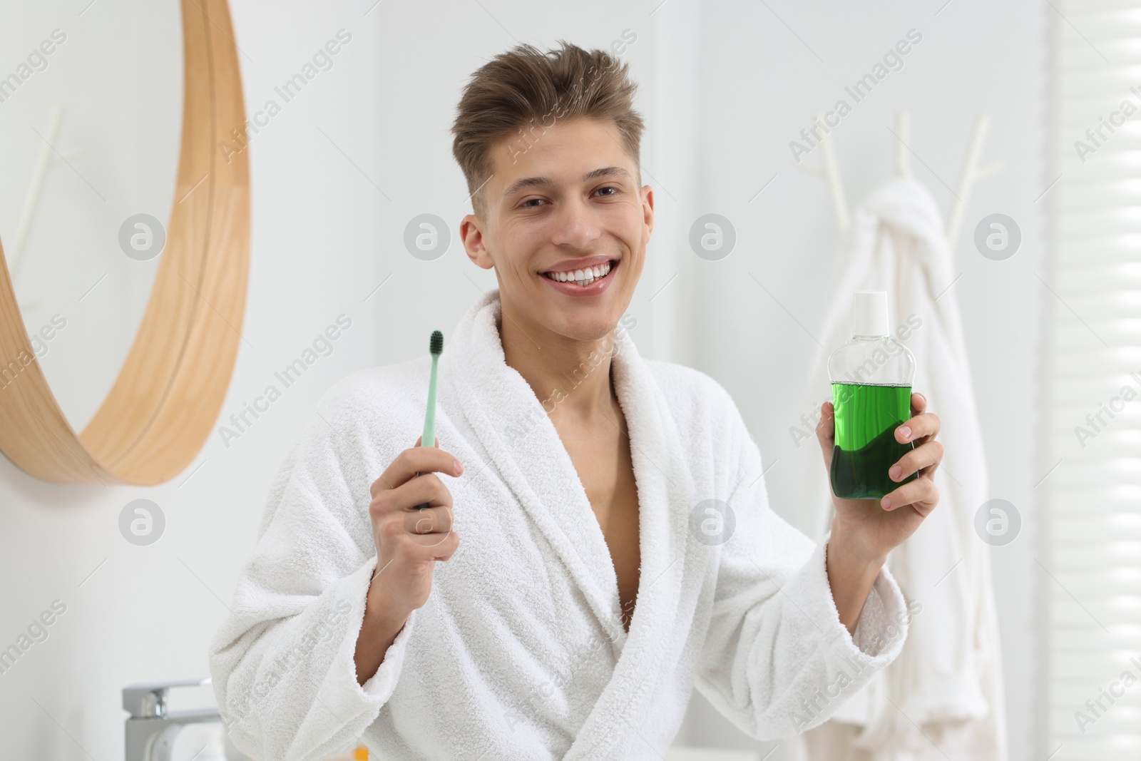 Photo of Young man with mouthwash and toothbrush in bathroom