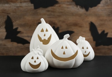 Jack-o-Lantern candle holders on black table against decorated wooden background. Halloween decor