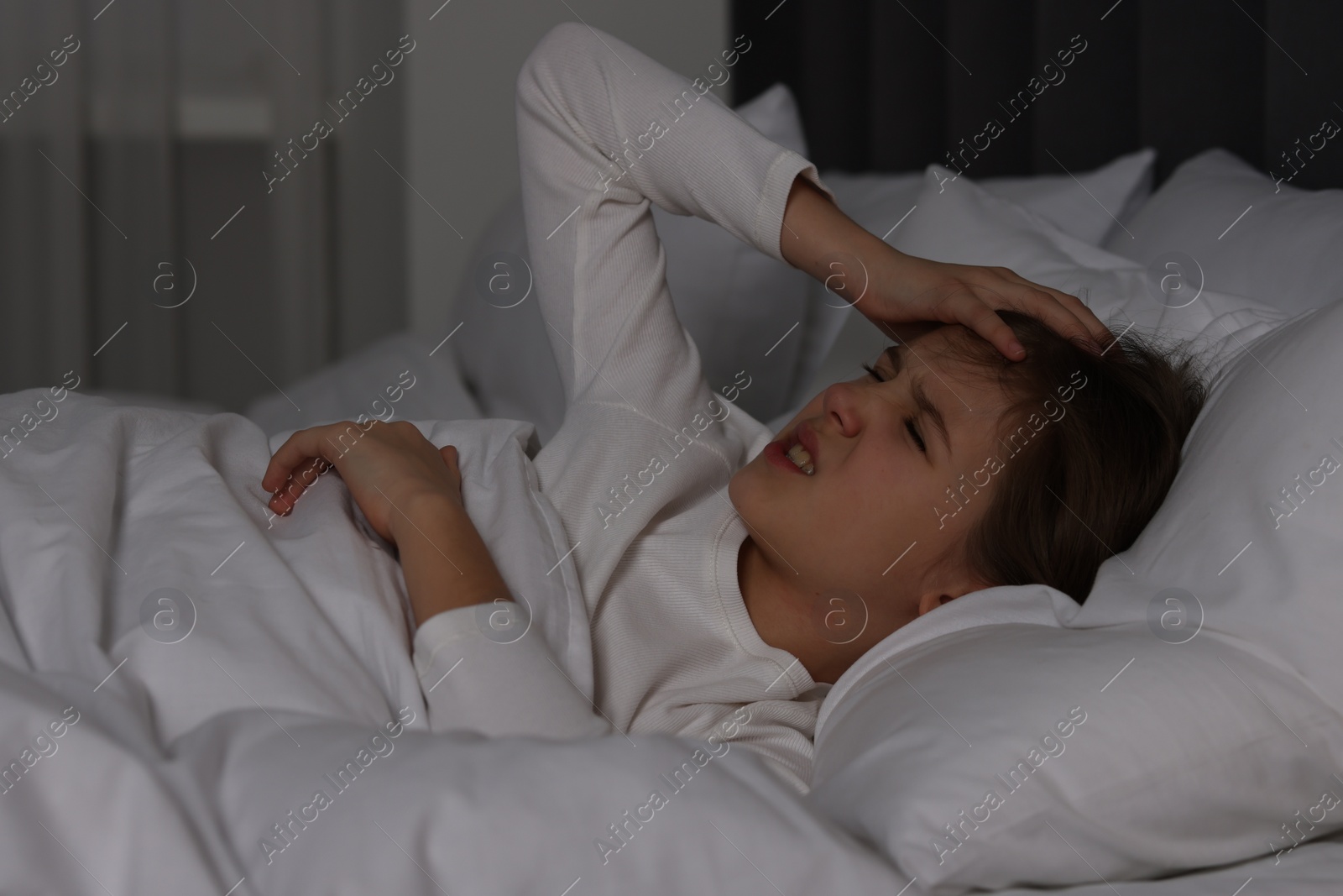 Photo of Little girl suffering from headache in bed at night