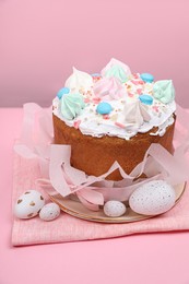 Traditional Easter cake with meringues and painted eggs on pink background