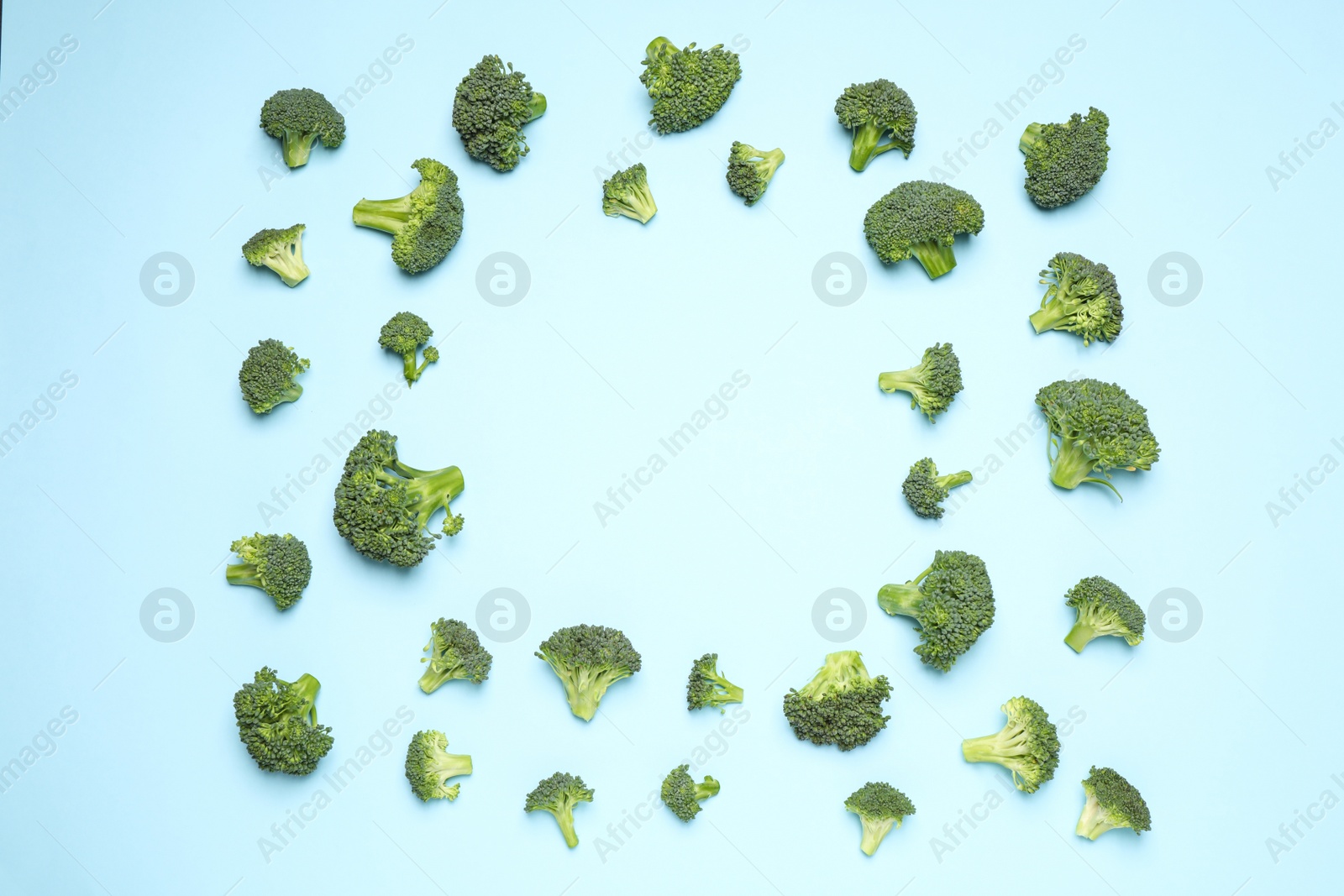 Photo of Fresh tasty broccoli on light blue background, flat lay. Space for text