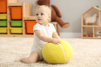 Photo of Children toys. Cute little boy playing with soft toy ball on rug at home