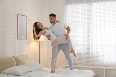 Photo of Lovely young couple dancing on bed at home