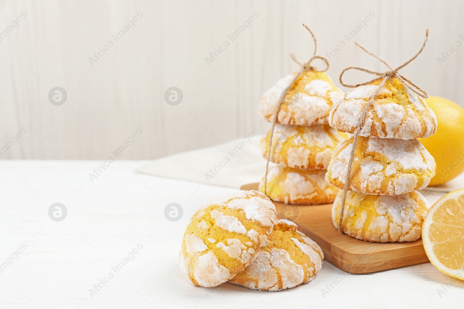 Photo of Tasty homemade lemon cookies and fresh fruits on white wooden table. Space for text