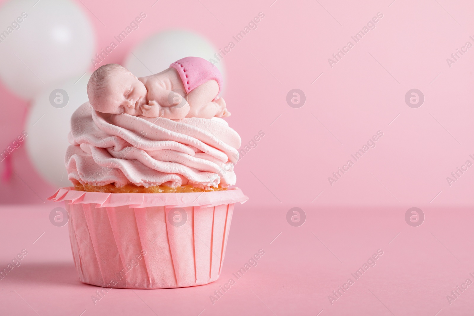 Photo of Beautifully decorated baby shower cupcake with cream and girl topper on pink background. Space for text