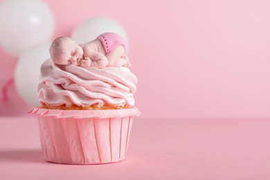 Beautifully decorated baby shower cupcake with cream and girl topper on pink background. Space for text