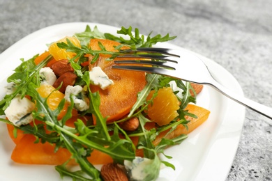Photo of Delicious persimmon salad served on grey table, closeup