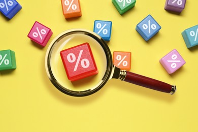 Image of Best mortgage interest rate. Cube with percent sign on yellow background, view through magnifying glass