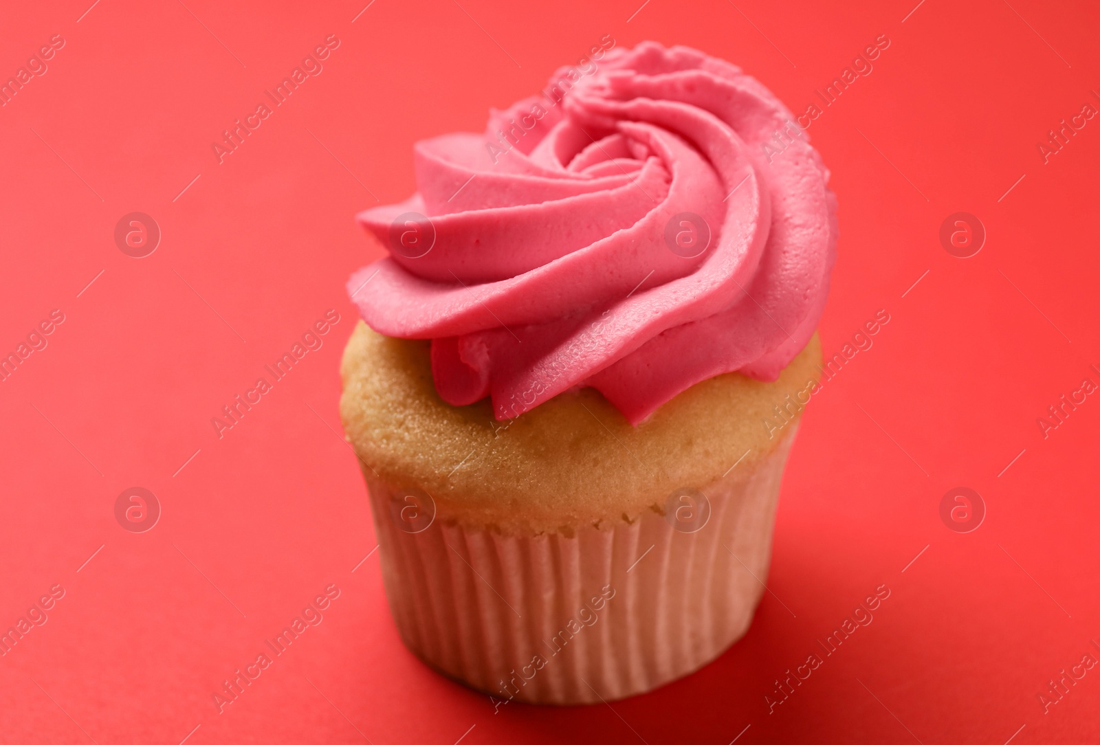 Photo of Delicious cupcake with bright cream on red background