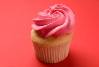 Photo of Delicious cupcake with bright cream on red background