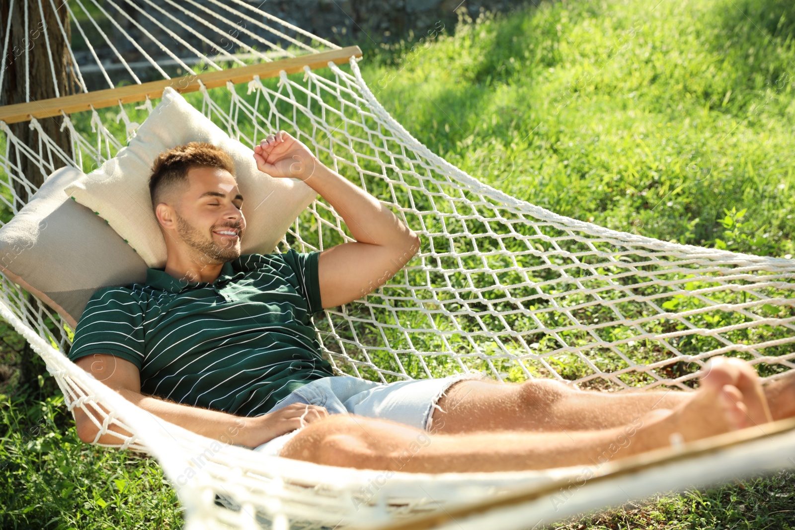 Photo of Young man resting in comfortable hammock at green garden